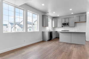 Contemporary kitchen featuring light gray cabinetry, white countertops, and stainless steel appliances