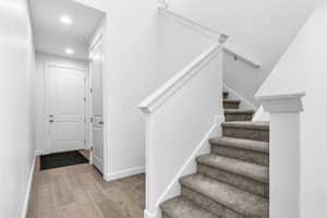 Carpeted staircase featuring a light-toned handrail and white balustrade