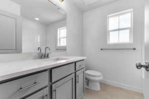 Modern bathroom featuring a single vanity with a light gray cabinet base, chrome hardware, and a white countertop