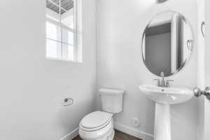 Pedestal sink with chrome faucet, circular mirror, and white toilet