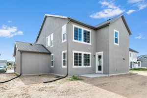 Exterior stucco finish with white trim windows and a rear patio