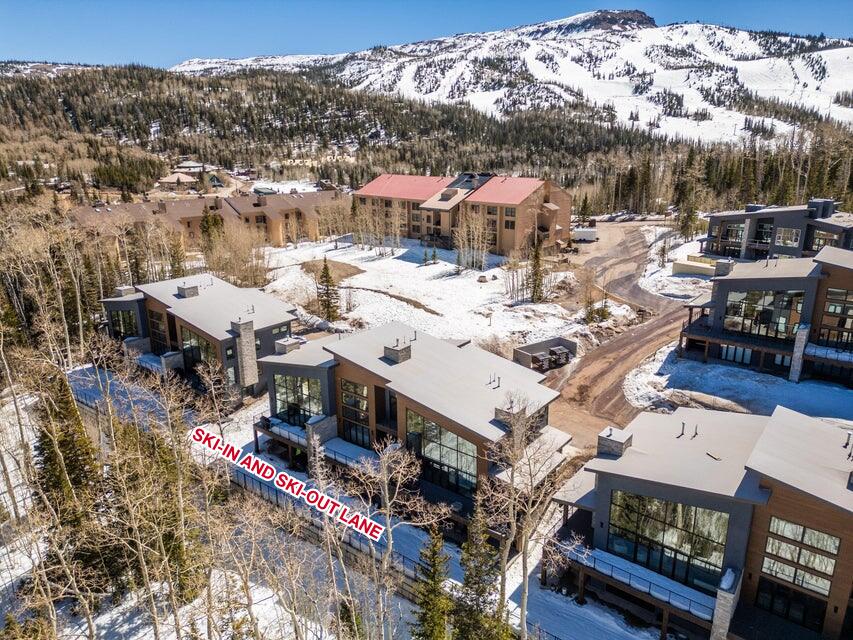 Modern mountain residences featuring expansive windows, wood-finish siding, and stone accents