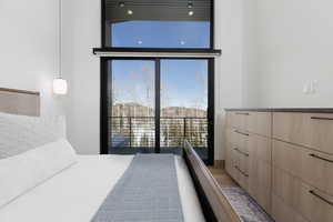 Bedroom featuring light wood finished floors, built in dressers, expansive windows, and a mountain view
