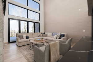 Living room featuring healthy amount of natural light, a high ceiling, and wood finished floors