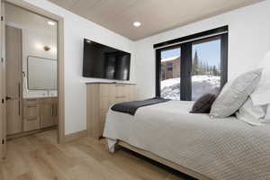 Bedroom featuring light wood-style flooring, recessed lighting, en-suite bathroom on main level