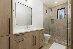 En-suite bathroom with vanity, a shower stall, light wood-style floors, and recessed lighting