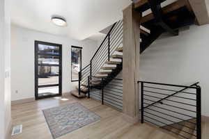 Entrance foyer with stairs going up and going down and light wood-style flooring