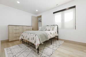 Bedroom featuring light wood-type flooring, built in dresser and recessed lighting