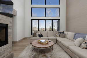 Living area with a fireplace, light wood-style floors, and a high ceiling
