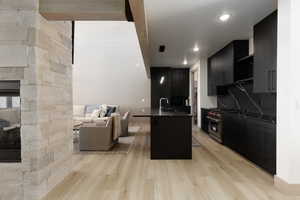 Kitchen with dark cabinets, WOLF luxury range, decorative light fixtures, open floor plan, and light wood-style flooring