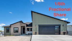 View of front facade with stone siding, board and batten siding, a garage, and driveway