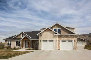Craftsman inspired home with board and batten siding, concrete driveway, and stone siding