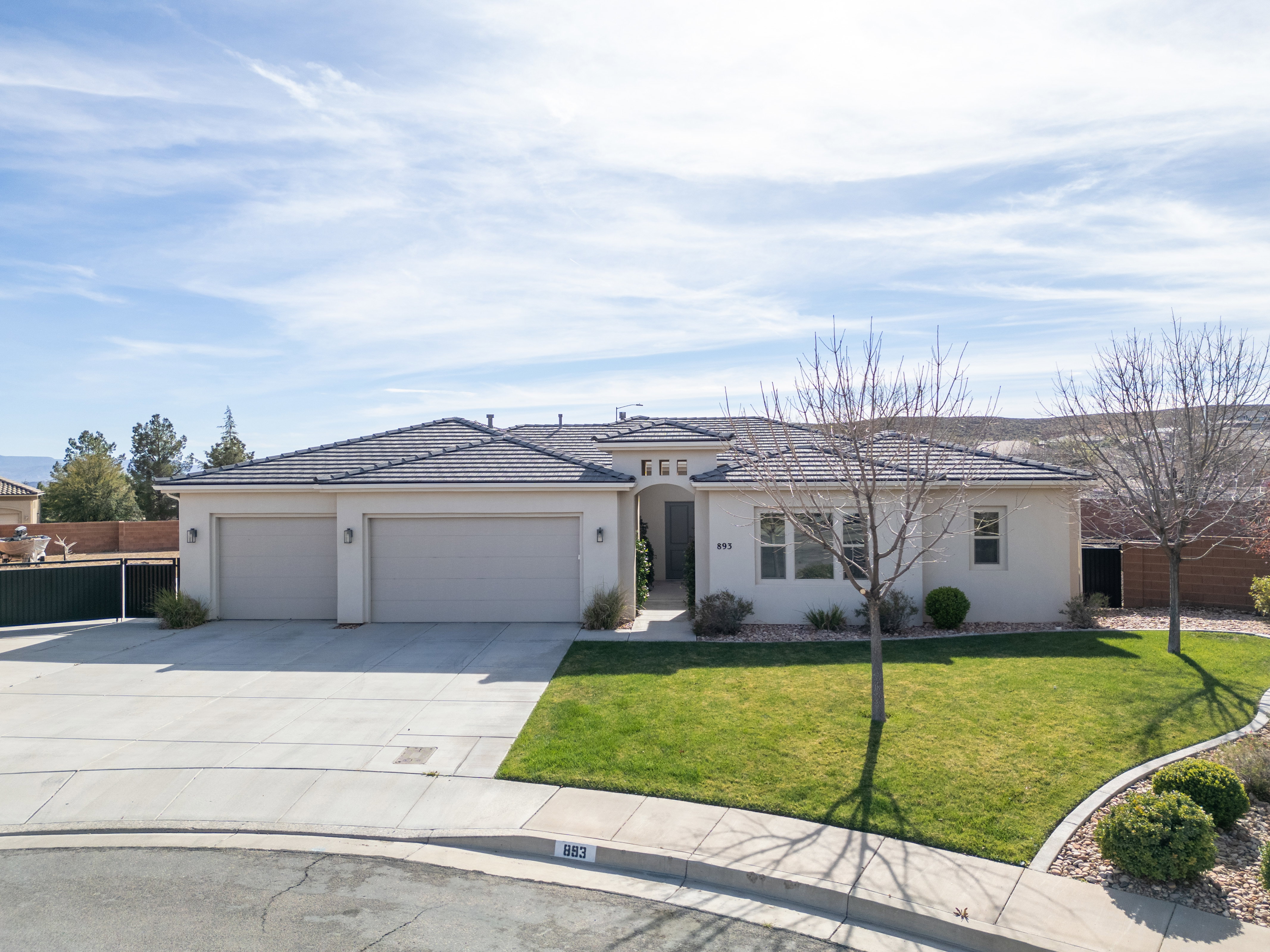View of front of property featuring an attached garage, concrete driveway, and stucco siding