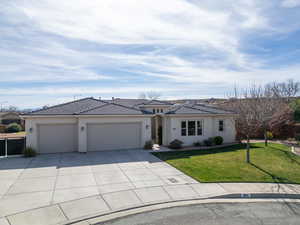 Prairie-style house with a garage, a front yard, stucco siding, driveway, and a tiled roof