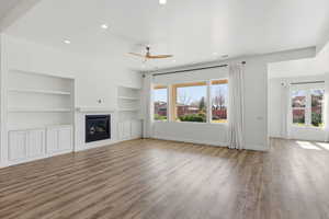 Unfurnished living room with ceiling fan, light wood-type flooring, built in shelves, healthy amount of natural light, and recessed lighting