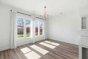 Unfurnished dining area with a chandelier and light wood-type flooring