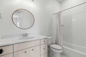 Bathroom featuring vanity, shower / bath combo with shower curtain, and light tile patterned flooring