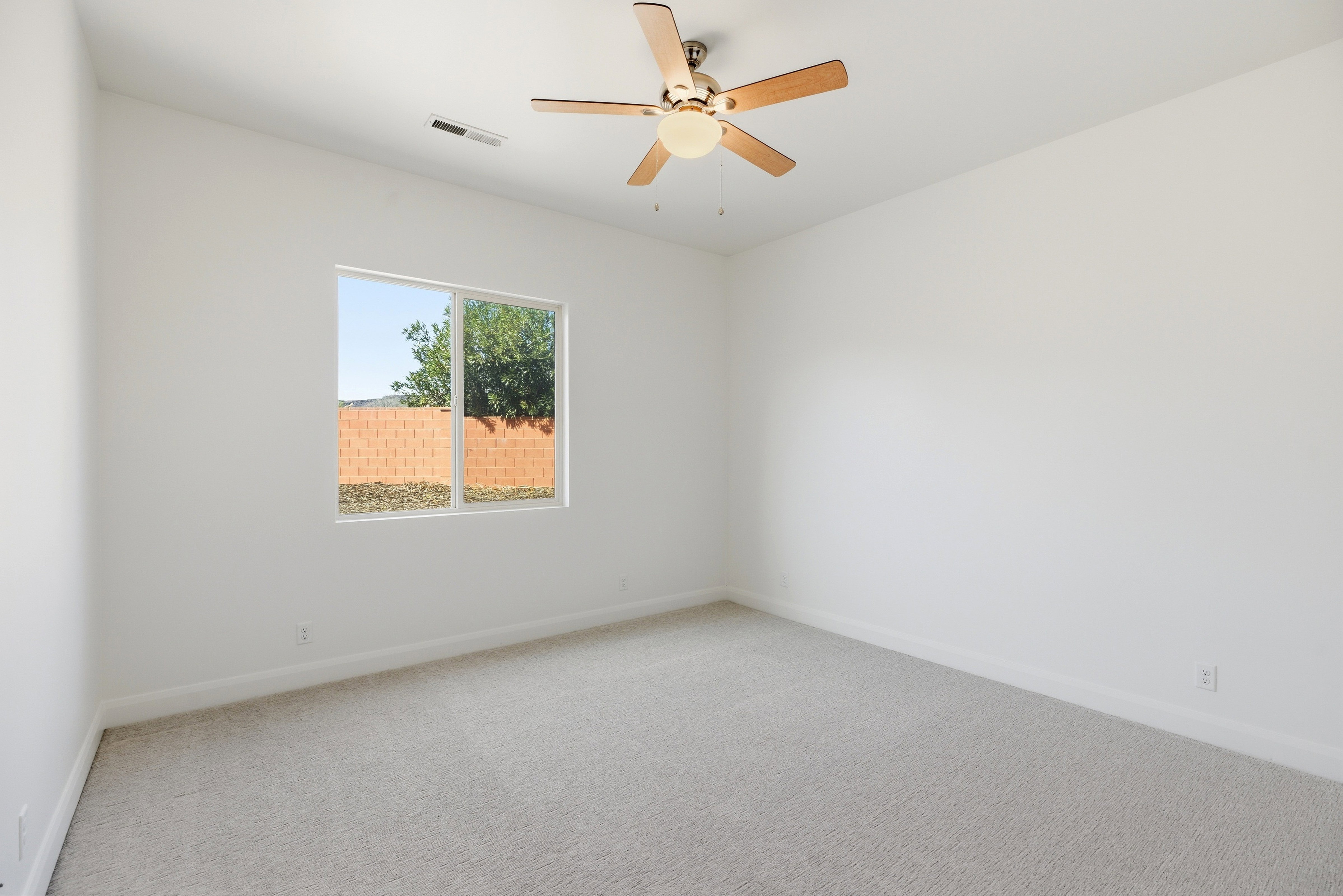 Spare room featuring light colored carpet and a ceiling fan