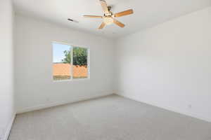 Spare room featuring light colored carpet and a ceiling fan