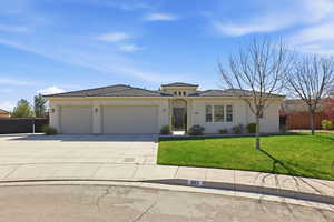 View of front facade featuring a garage, driveway, a tiled roof, and stucco siding