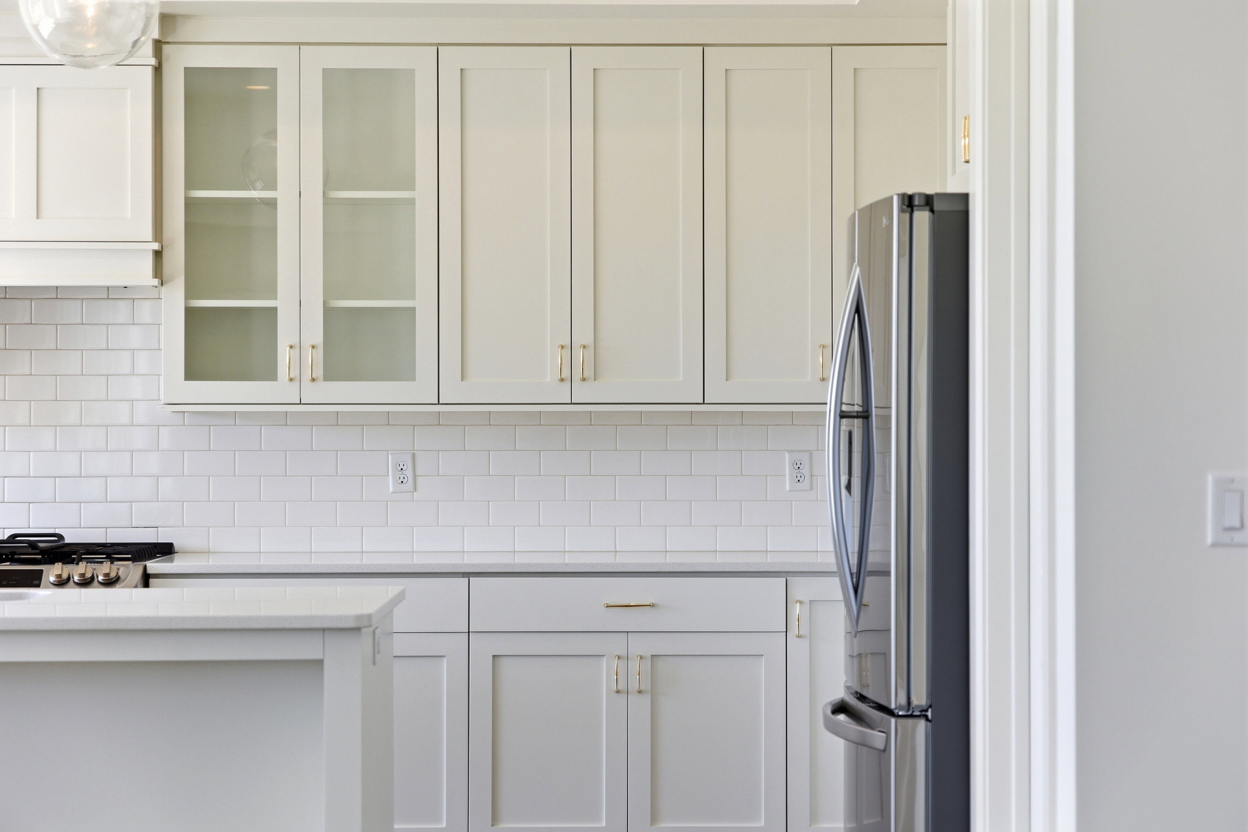 Kitchen with glass fronted cabinets, stainless steel appliances, tasteful backsplash, and white cabinets
