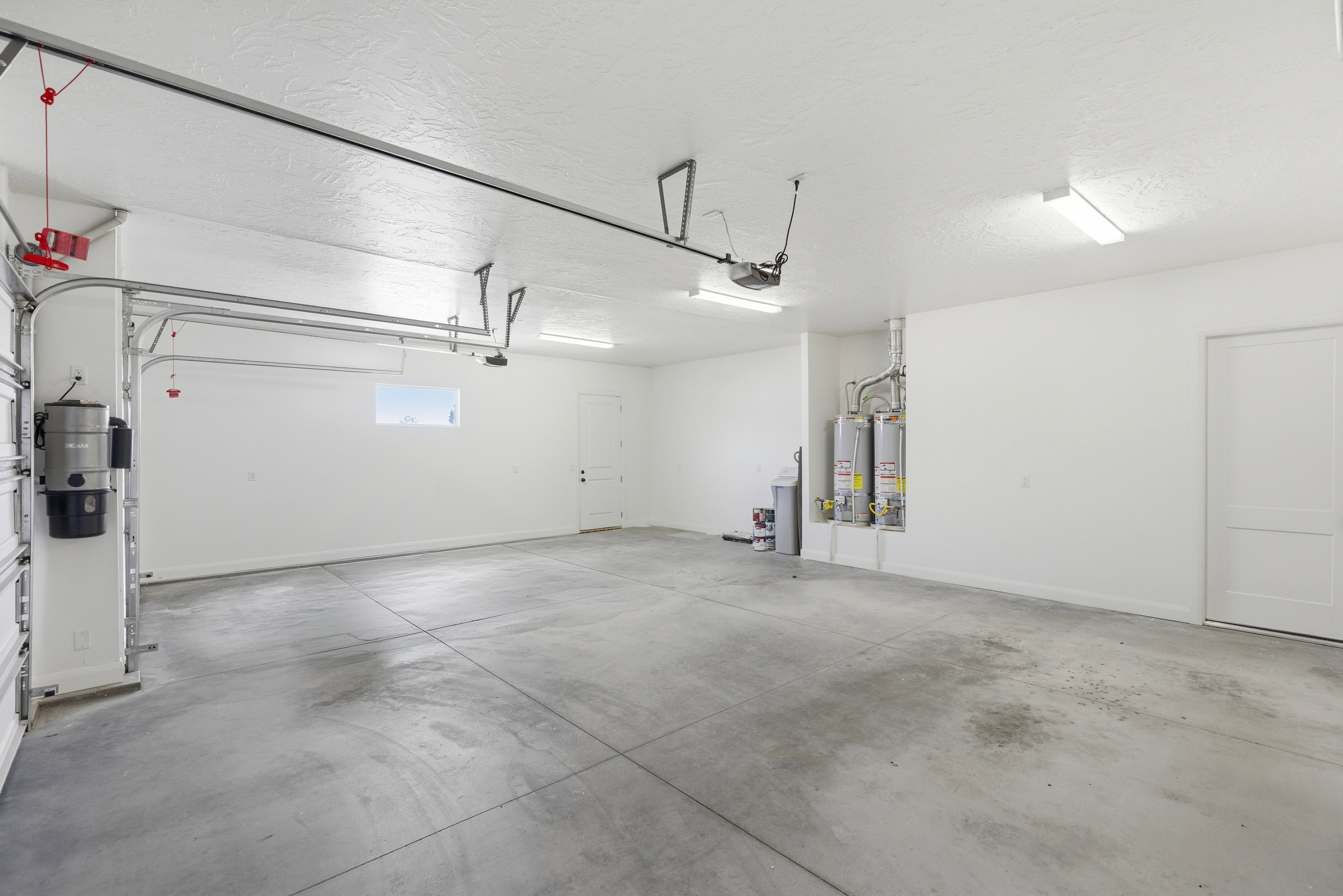 Garage featuring a central vacuum unit and gas water heater