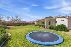 Fenced backyard with a trampoline and a patio area