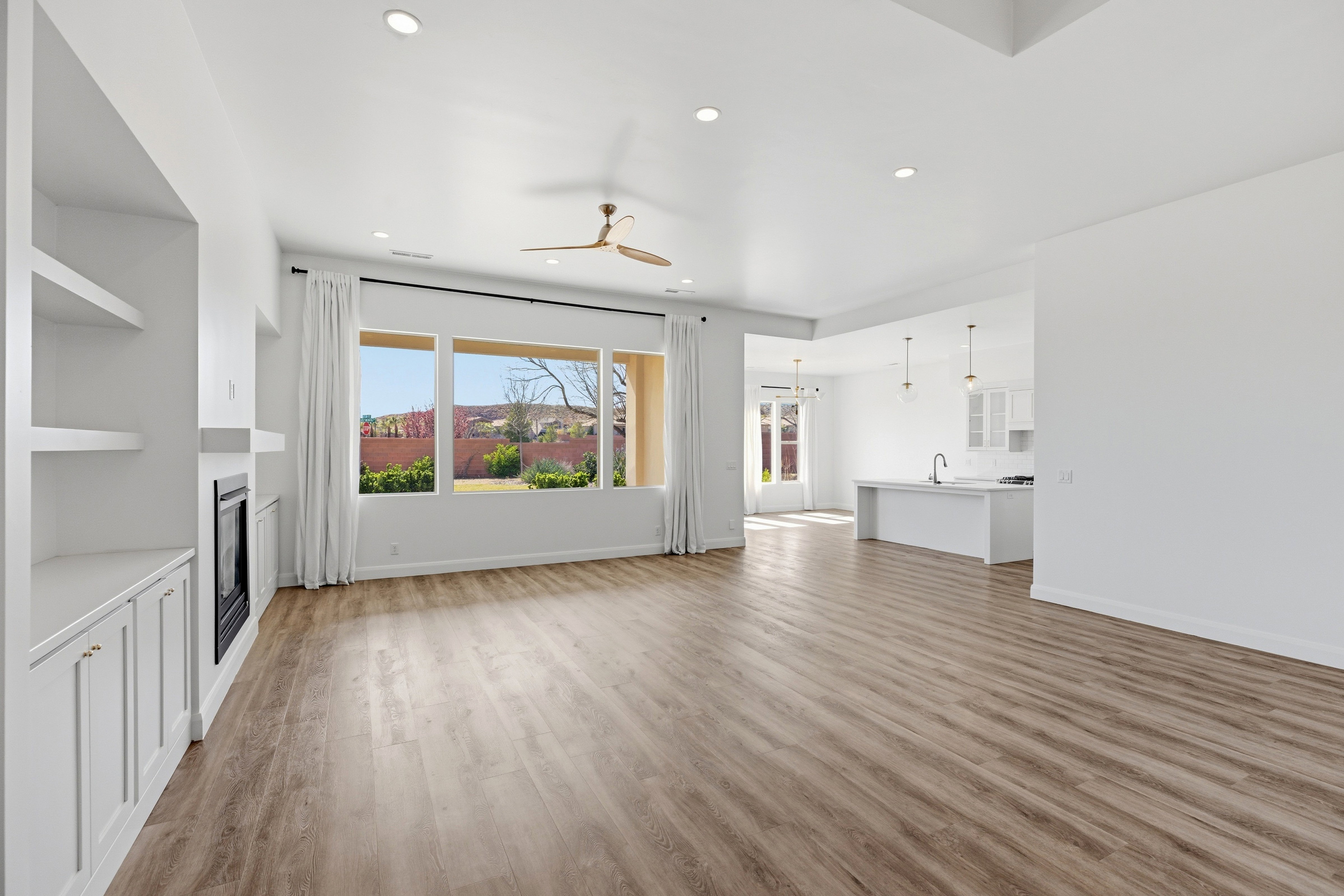 Unfurnished living room with ceiling fan, light wood-type flooring, recessed lighting, and a glass covered fireplace