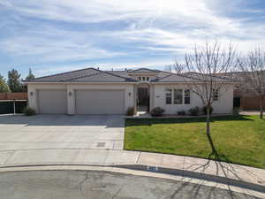 View of front of house with an attached garage, concrete driveway, stucco siding, and a tiled roof