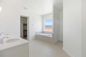 Full bath featuring double vanity, a bath, a walk in closet, and light tile patterned floors