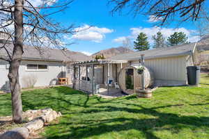 Rear view of property with a lawn, a mountain view, a patio, and roof with shingles