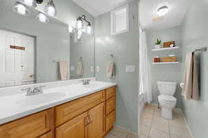 Full bath with double vanity, light tile patterned flooring, and shower / tub combo with curtain
