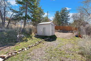 Fenced backyard featuring a storage unit