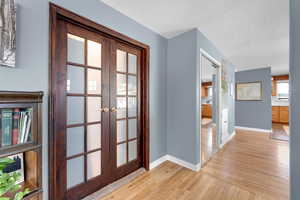 Hallway with french doors, light wood-style flooring, and a textured ceiling