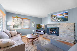 Living room featuring a stone fireplace and wood finished floors