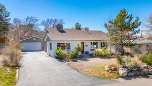 Ranch-style house with a shingled roof, a chimney, and a detached garage