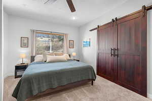 Carpeted bedroom with a barn door, ceiling fan, recessed lighting, and a textured ceiling
