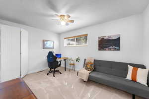 Carpeted office with a ceiling fan and a textured ceiling
