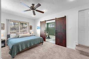 Bedroom featuring a barn door, light colored carpet, ceiling fan, a textured ceiling, and recessed lighting