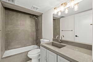 Full bath with vanity,  shower combination, and a textured ceiling