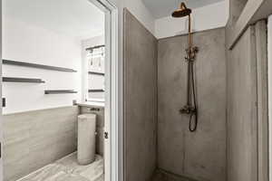 Bathroom with tile walls, a marble finish shower, and a wainscoted wall
