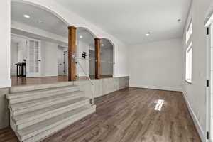 Entryway featuring arched walkways, dark wood-style flooring, and ornate columns