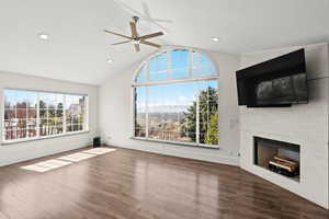 Unfurnished living room with a large fireplace, ceiling fan, dark wood-style floors, a high ceiling, and recessed lighting