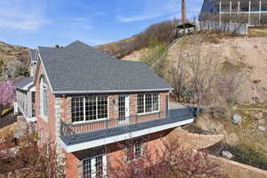 View of home's exterior featuring brick siding, french doors, a balcony, and a shingled roof