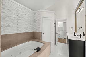 Bathroom with vanity, light tile patterned floors, a jetted tub, and a walk in closet