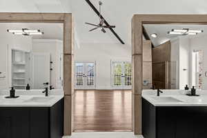 Bathroom with two vanities, french doors, vaulted ceiling, healthy amount of natural light, and ceiling fan