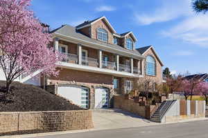 View of front of home featuring concrete driveway, an attached garage, a balcony, stone siding, and brick siding