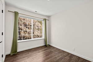 Unfurnished room featuring dark wood-style floors and baseboards