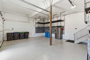 Garage with stainless steel refrigerator with ice dispenser and a garage door opener