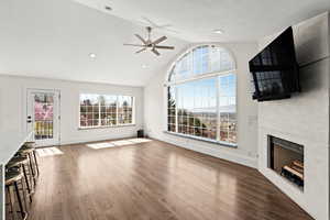 Unfurnished living room with ceiling fan, a fireplace, dark wood-type flooring, and lofted ceiling